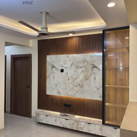 Newly handed-over living room with a fluted walnut TV wall, a veined stone panel lit from below, and a black-framed glass display unit built beside it.
