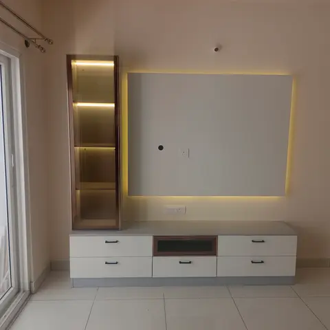 Newly installed TV console with a backlit white panel wall and an adjoining glass-front display cabinet with integrated shelf lighting, not yet styled.