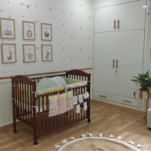 Nursery with a wooden crib fitted with a canopy and bumper, a two-tone wainscot wall, a gallery of framed animal illustrations