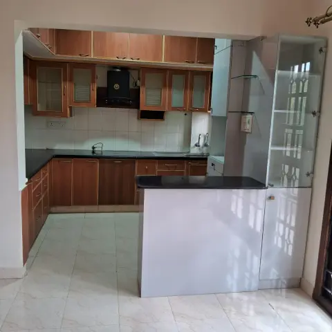 Older U-shaped kitchen seen through its opening from an empty adjoining room - teak-laminate cabinets with gold beading and frosted-glass shutters