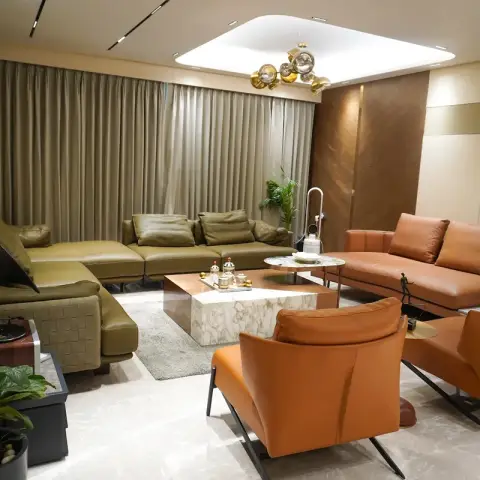 Olive leather sectional facing two tan leather swivel loungers around a solid marble block coffee table