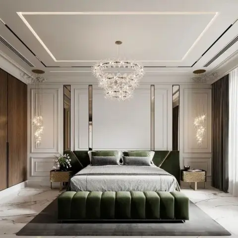 Olive-velvet bed and matching channel-tufted foot bench under a floral crystal chandelier, flanked by ivory moulded panels with slim bronze mirror strips.