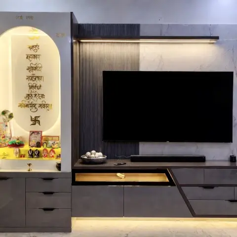 One wall carrying both a backlit arched pooja niche with a gold Sanskrit shloka on its back panel and a TV bay in grey veined marble with a dark fluted panel