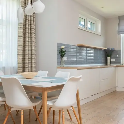 Open dining and kitchen area with a six-seat wood dining table under a cluster pendant light