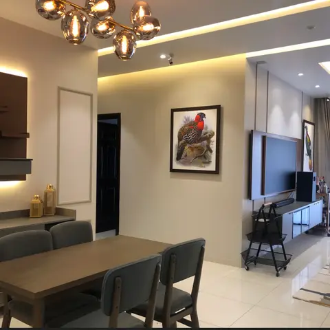 Open dining and living area with a wood dining table, a globe-bulb chandelier, framed bird art on the wall, and a floating TV console under cove lighting.