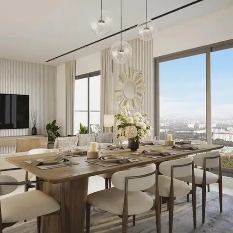 Open dining and living space with a wood dining table for eight under glass globe pendants, a fluted panel wall, and a sunburst mirror by the window.
