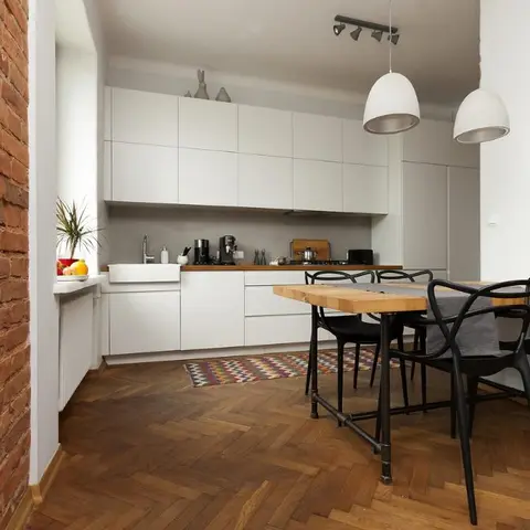 Open dining nook with a reclaimed-wood table and black wishbone-style chairs beneath concrete pendant lights