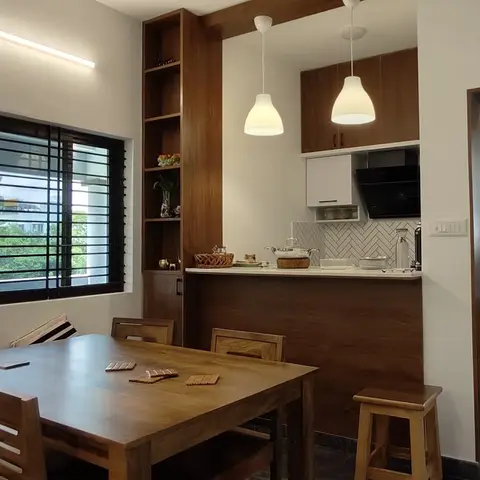 Open dining nook with a wooden table for six flowing into a compact kitchen with herringbone-tile backsplash and walnut cabinetry