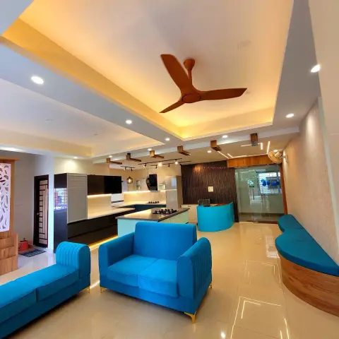 Open floor where electric-blue channel-tufted sofas sit in front of a black-and-white island kitchen