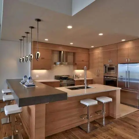 Open island kitchen with wood-veneer flat-panel cabinets, a cascading row of teardrop pendant lights, integrated stainless steel refrigerator and wall oven