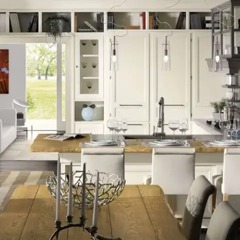 Open kitchen-diner in cream shaker cabinetry that runs floor to ceiling with a rolling library ladder, glass display cupboards on both sides