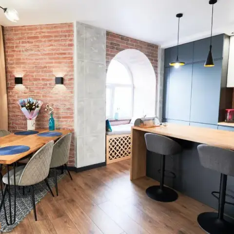 Open kitchen island in graphite-blue handleless cabinetry under black pendant lights