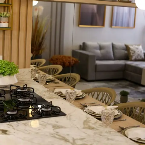 Open kitchen island with a marble counter and built-in gas hob extending into a laid dining table