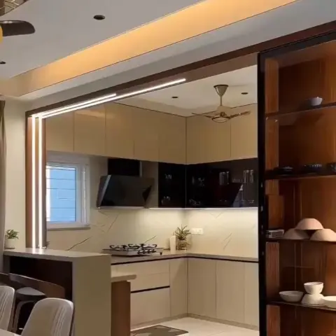 Open kitchen seen through a doorway with a linear ceiling light strip, glossy black-and-beige cabinets, and a marble-look backsplash