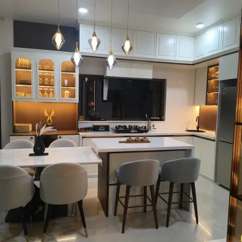 Open kitchen with a quartz-topped island in fluted wood facing two grey bar stools, six faceted smoked-glass pendants strung above in a staggered line