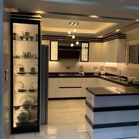Open kitchen with a stepped white-and-black gloss breakfast peninsula, black counters throughout