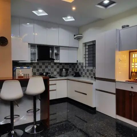 Open kitchen with a wood-edged breakfast counter and two white bar stools, a grey patchwork-pattern dado behind the hob