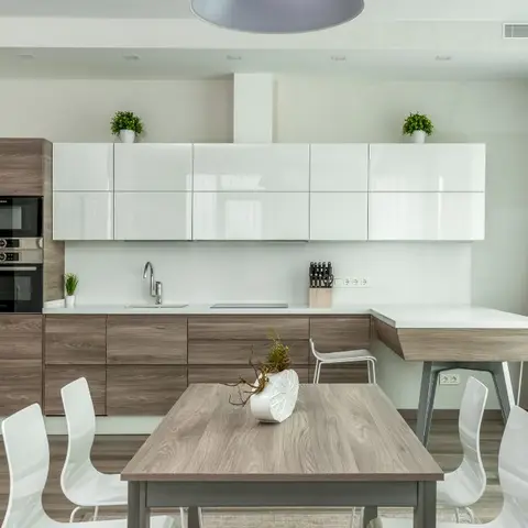 Open kitchen with white high-gloss overhead cabinets and wood-grain base units, a built-in oven and microwave column