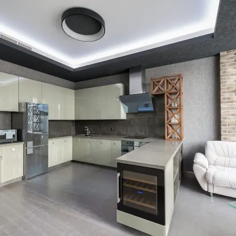 Open L-shaped kitchen with pista-green high-gloss cabinetry and a peninsula counter housing a built-in wine cooler