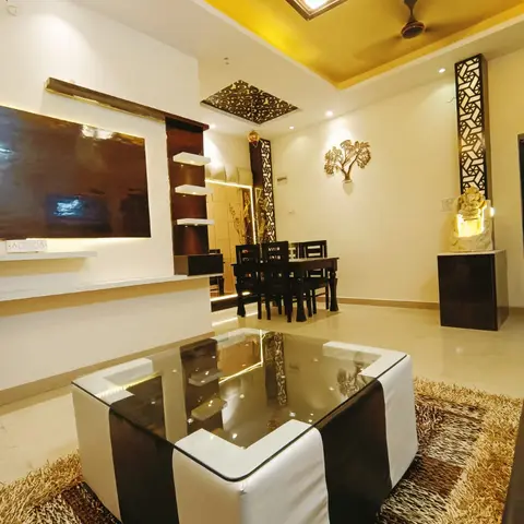 Open living-dining space with a mustard-yellow pop ceiling with cutout jaali detailing, carved wooden jaali pillars