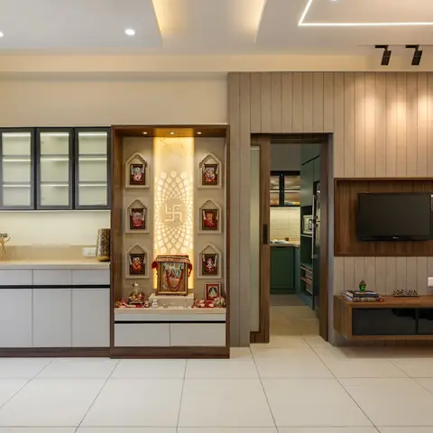 Open living space showing a backlit pooja niche with a lotus motif and deity frames