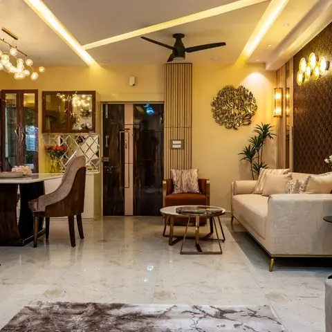 Open living space with a fluted TV feature wall, angular cove-lit ceiling, brass wall sconces, a round brass jaali wall clock