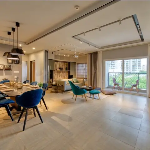 Open-plan apartment showing a dining set with navy velvet chairs under twin pendant lights, a living seating area with a teal accent chair