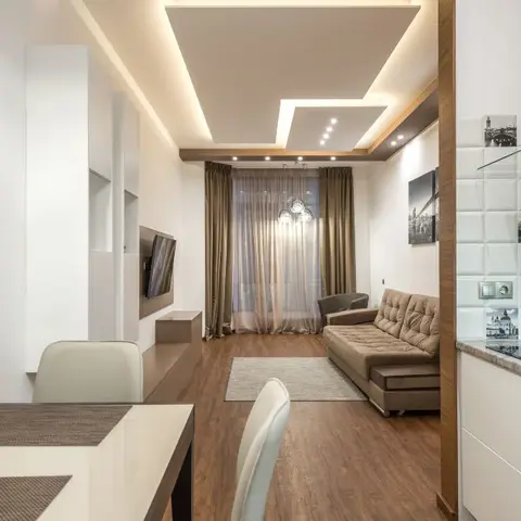 Open-plan apartment view from the dining table through to the kitchen counter and living sofa in one frame