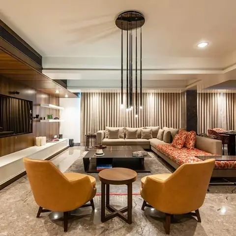 Open-plan basement living area with a wood-veneer TV feature wall and large art panel, mustard leather armchairs, a red-and-white patterned sectional sofa