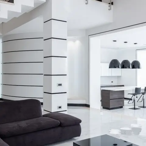 Open-plan black-and-white home showing a dark velvet sectional beside a curved ribbed feature wall