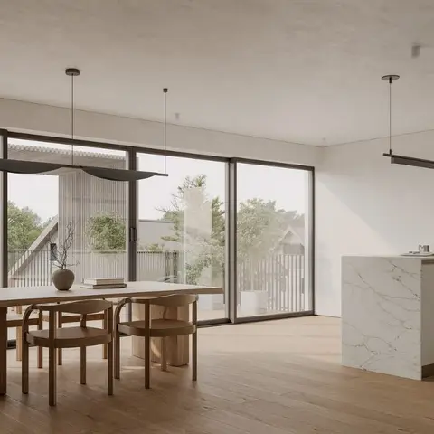 Open-plan dining and kitchen with a wood dining table under a sculptural pendant light, full-height glazing to a deck