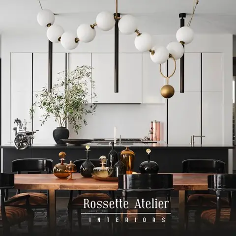 Open-plan dining and kitchen with a black-and-brass sculptural globe chandelier over a live-edge wood table, black island cabinetry