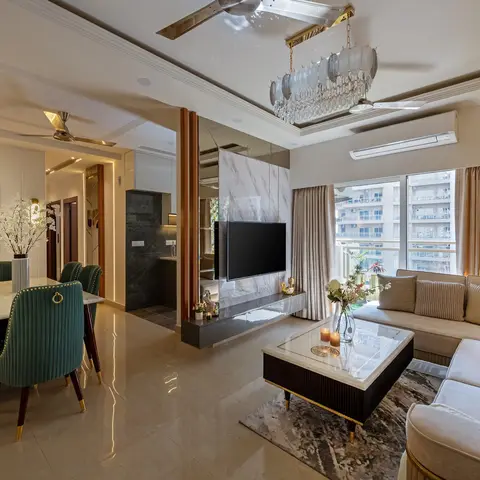 Open-plan dining and living area with a marble-top dining table and brass-studded emerald velvet chairs on one side