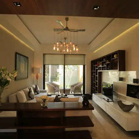 Open-plan dining and living space with a dark wood console table in the foreground, a cluster pendant chandelier