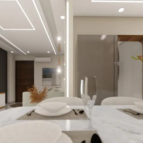 Open-plan dining table in the foreground with a marble-look TV feature wall and a built-in fridge nook visible beyond