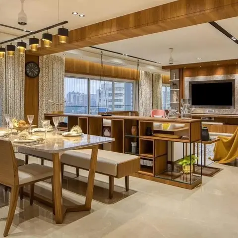 Open-plan dining table with bench seating beside a wood-and-glass display divider unit opening into a living/TV area
