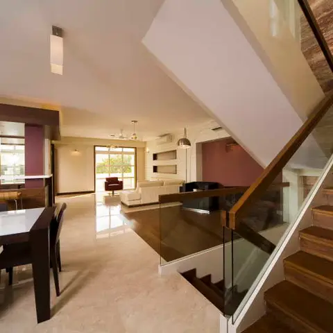 Open-plan duplex landing with a floating staircase in walnut-toned wood beside a dining and living area below.