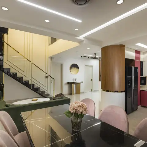 Open-plan duplex space showing a black marble dining table with pink velvet chairs, a green sofa lounge beneath a floating staircase