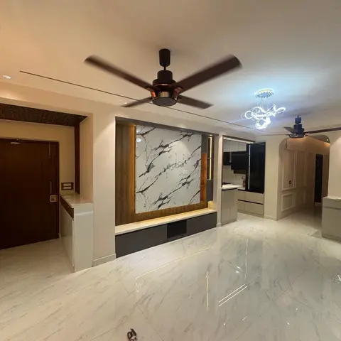 Open-plan entrance and living area with a book-matched marble accent wall flanked by fluted wood insets, a floating dark TV console