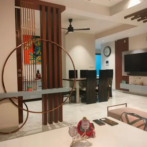 Open-plan entrance, dining and living space seen through a copper-ring and wood-slat partition screen