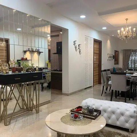 Open-plan entry, kitchen and dining area with a full-height mirrored console wall, a crystal chandelier over the dining table