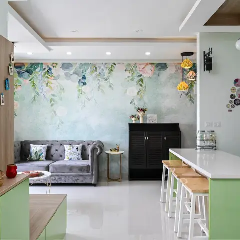 Open-plan flat shot end to end: a grey velvet chesterfield against a hand-painted trailing-floral mural