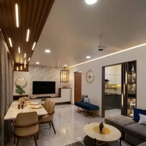 Open-plan flat shot lengthwise from the sofa: fluted-wood ceiling raft with recessed linear lights over a marble dining table