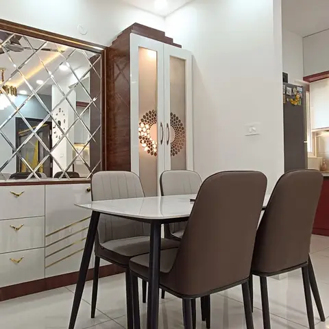 Open-plan frame showing a dark wood entry door and diamond-mirror console unit beside a dining table, with a maroon-and-white modular kitchen visible beyond.