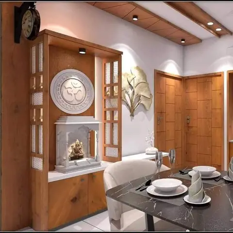 Open-plan frame with a carved wood pooja unit bearing a marble Om medallion on one side and a dining table setting on the other, neither zone dominant.