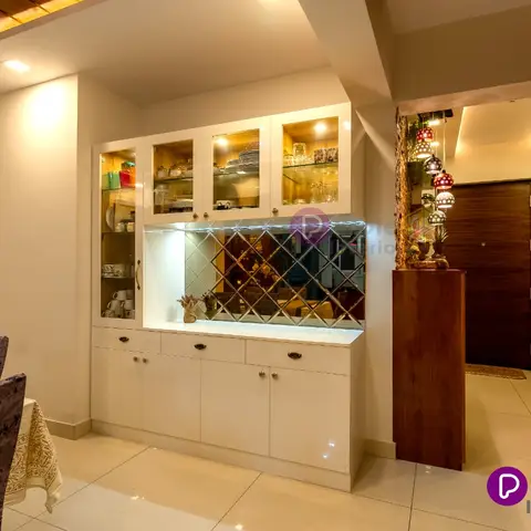 Open-plan frame with a mirrored glass-front crockery unit between the dining area and an entrance foyer with a dark wood main door and a hanging Moroccan-lamp