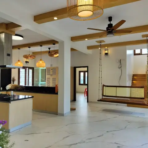 Open-plan hall with a black-granite island kitchen and stainless chimney at one end, woven cane pendants under a wooden beam grid