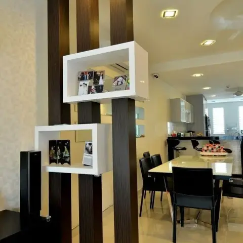 Open-plan home showing a dark wood-slat partition with floating white display cubes dividing the dining area from a kitchen counter with bar stools beyond.