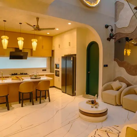 Open-plan kitchen and living space with mustard-yellow kitchen cabinetry, a white waterfall island under lantern pendant lights