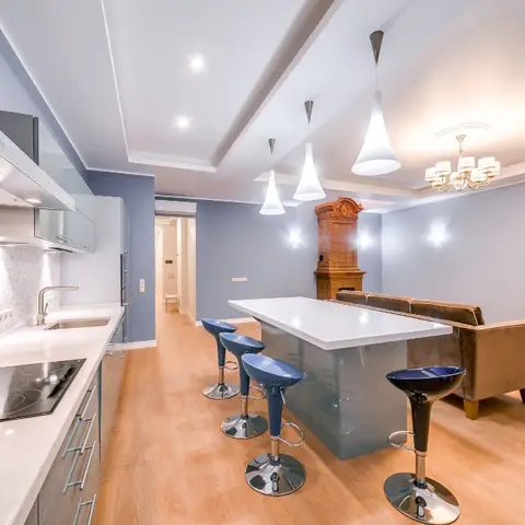 Open-plan kitchen and living space with a mosaic-tiled backsplash, a grey waterfall-edge island with blue barstools, pendant lighting